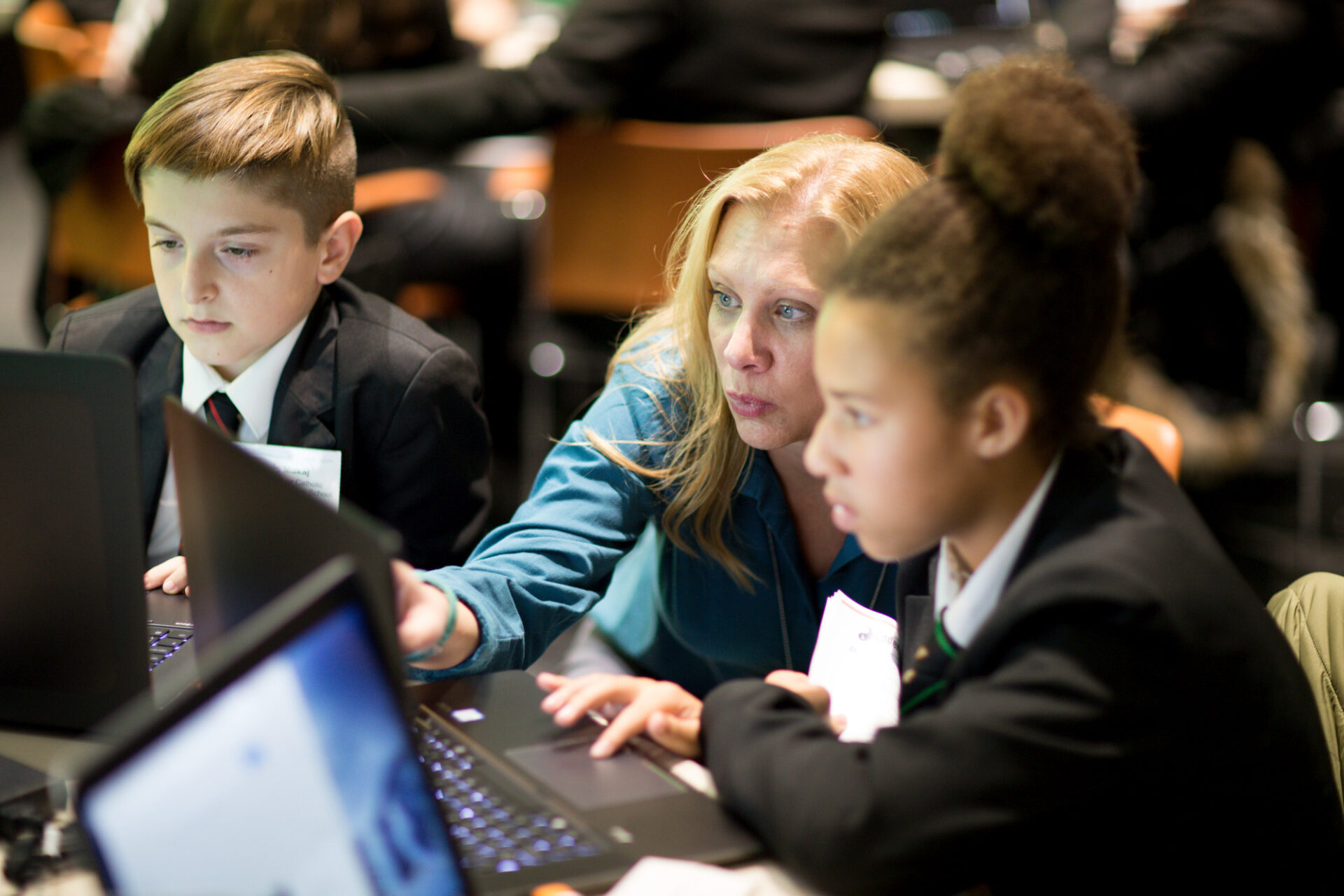 A woman is mentoring a young person, providing guidance as they work on a laptop together