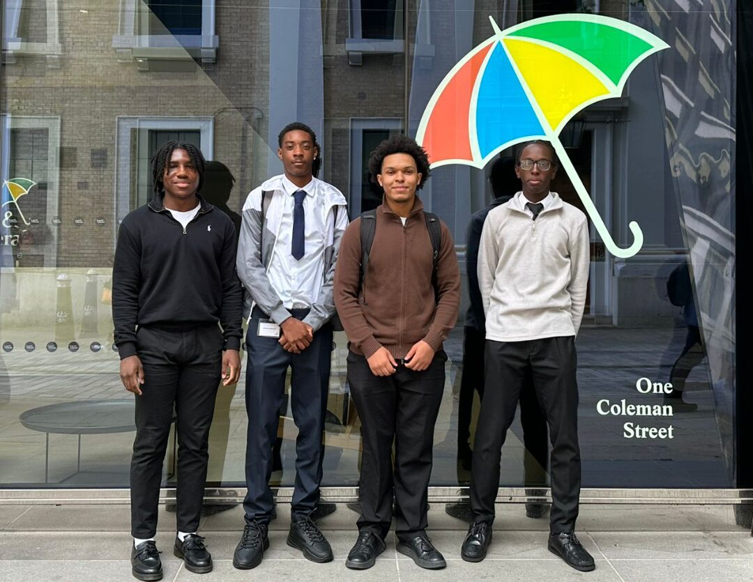 Four students at an Urban Synergy Corporate Insight Day standing next to the Legal and General logo