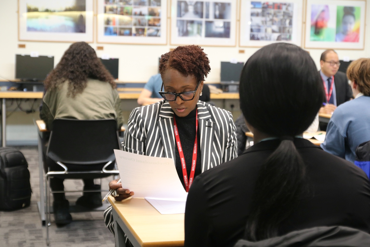 Mock interview at a school, an industry professional help a young woman prepare for job interviews