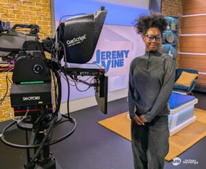 Young person poses near a television camera while undertaking work experience at ITN